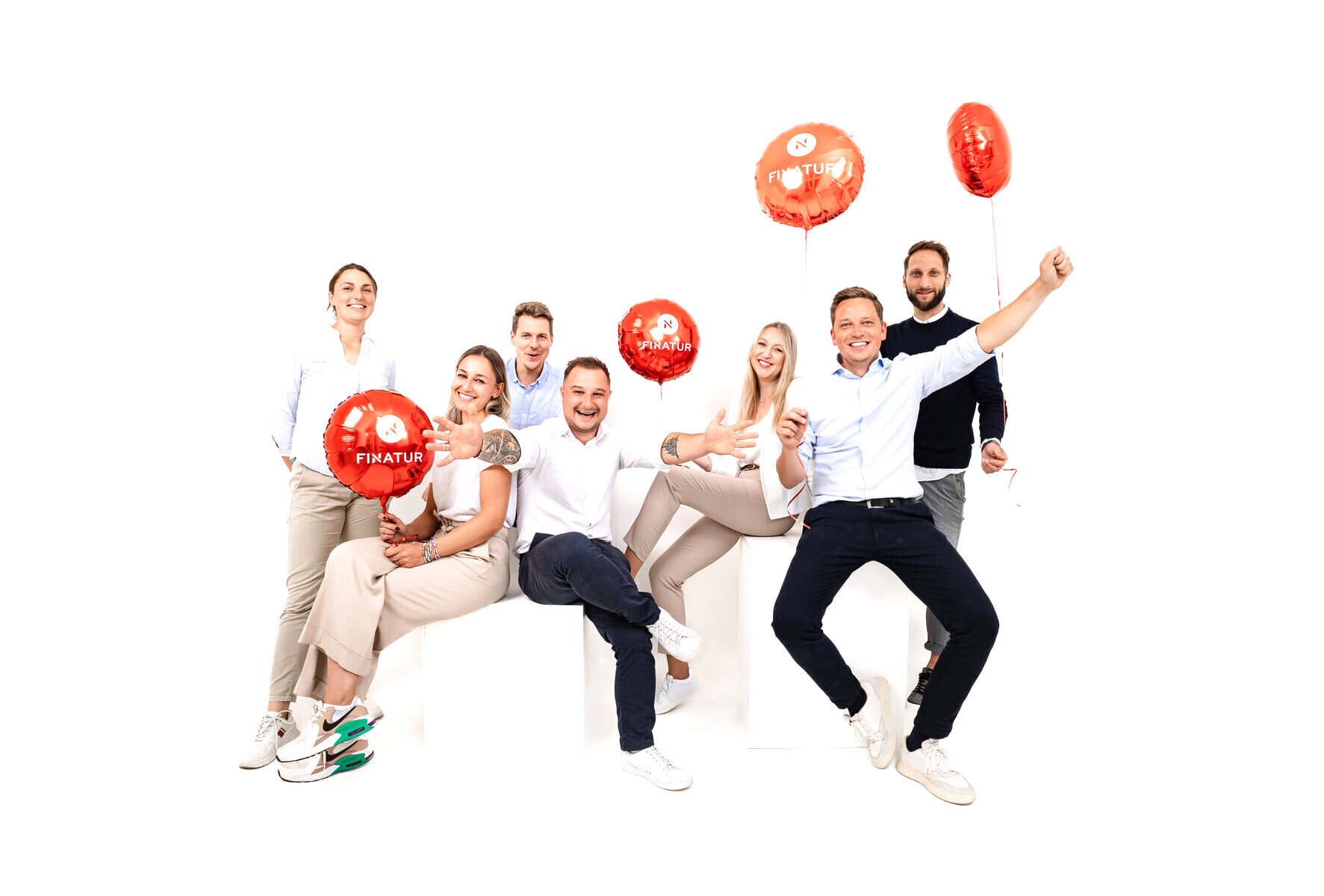 Das FINATUR-Team mit roten Markenballons beim gemeinsamen Fotoshooting im Studio