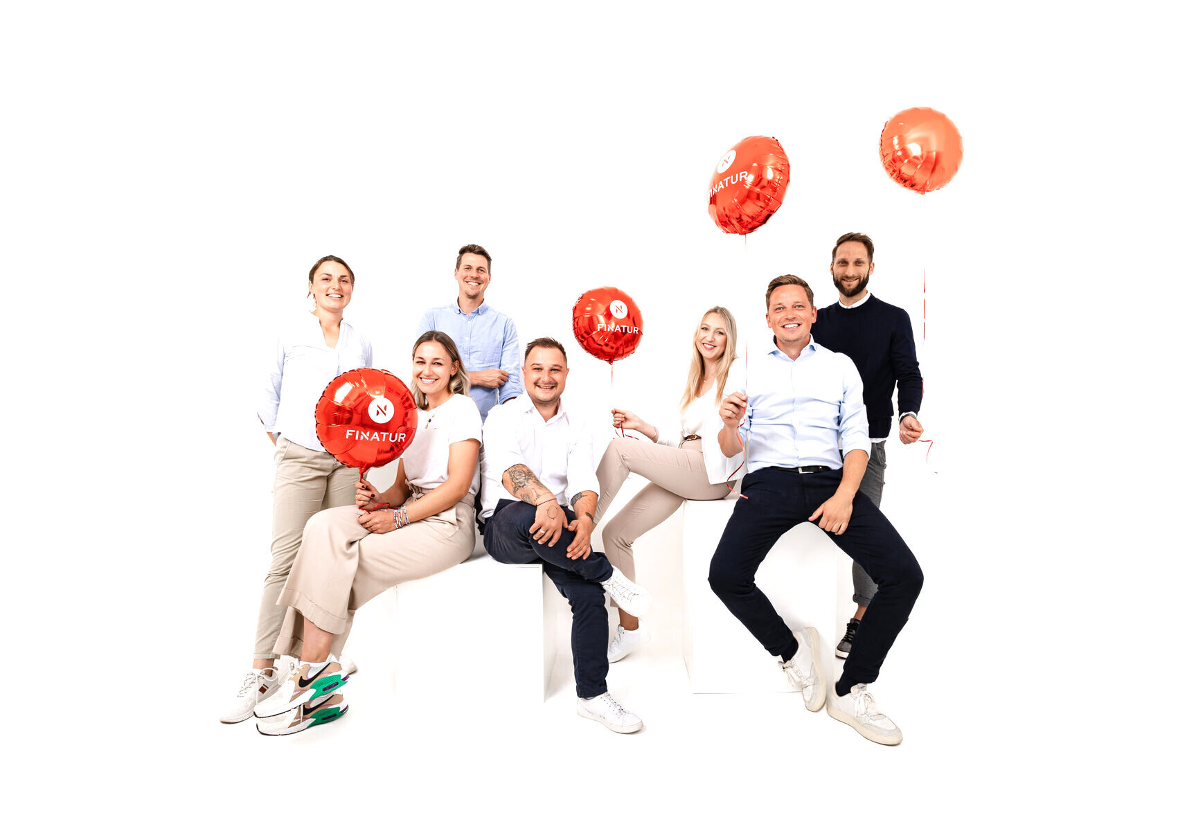 FINATUR-Team mit roten Logo-Luftballons
